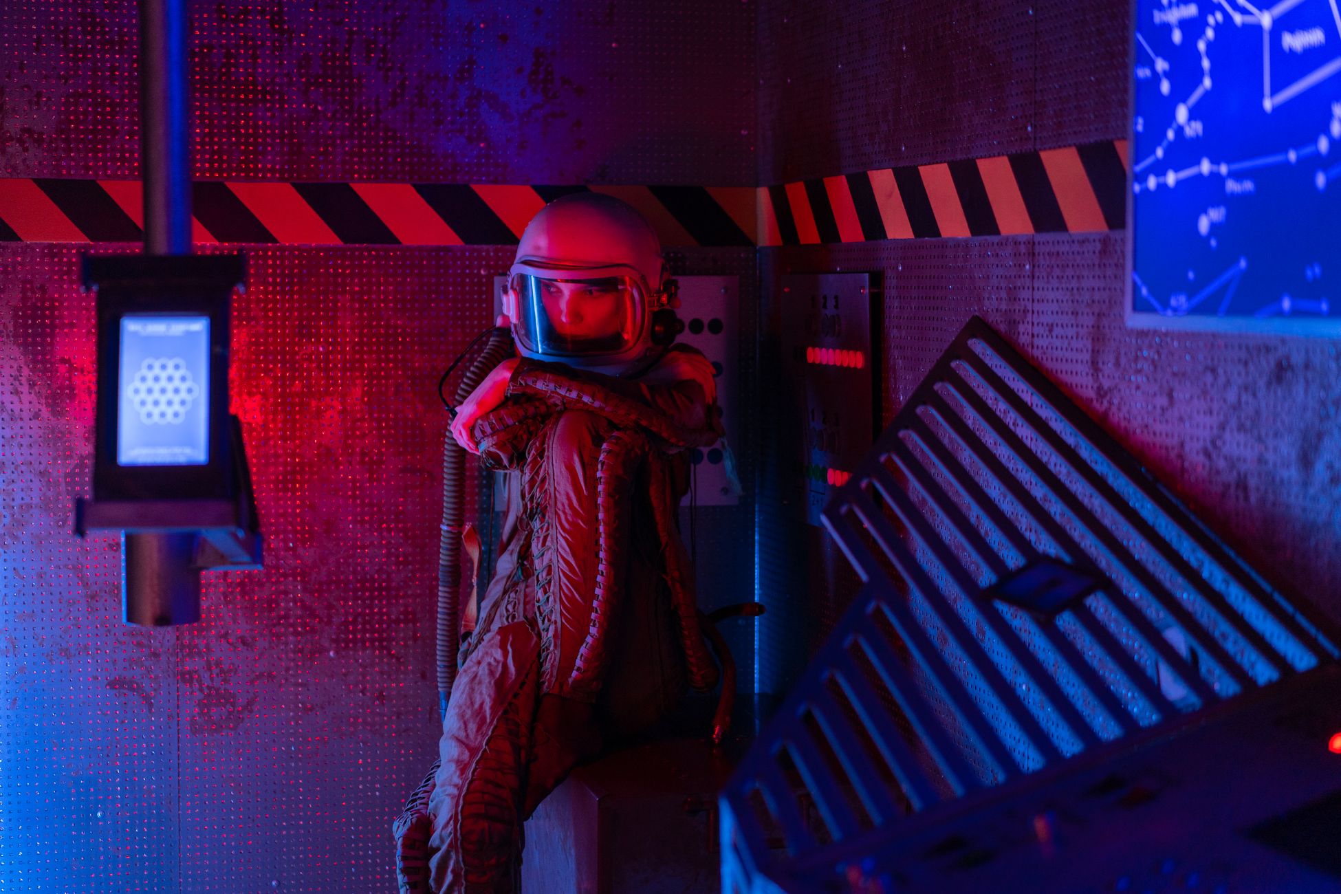 A spacewoman in a futuristic spacesuit sits thoughtfully inside a spacecraft.